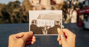 A person holds a photo of Istanbul with a famous mosque in the background, capturing both past and present.