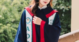 Young woman wearing graduation cap and gown, standing on a balcony.