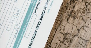 A credit card application form placed on a wooden surface, shot from above.