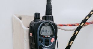 Closeup of a marine radio attached to a yacht, highlighting nautical ropes and communication equipment.