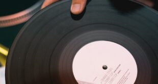 A close-up shot of a hand holding a vinyl record ready to play on a DJ mixer.