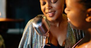 Two women singing together with a microphone in an indoor setting, showcasing their passion and talent.