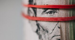 Closeup of rolled United States five dollar bills tightened with red rubber band