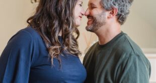 A joyful couple sharing an intimate moment while expecting their baby, indoors.