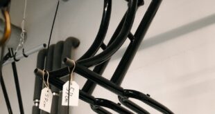 Hanging black steel bicycle frames in an Amsterdam workshop with natural lighting.