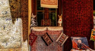 A vibrant display of rugs and figurines at a market stall, showcasing intricate designs and patterns.