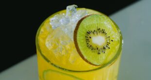 Vibrant yellow cocktail garnished with fresh kiwi slice and ice, perfect for a tropical refreshment.