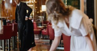 An elegant dining room with attentive waitstaff, red chairs, and sophisticated decor.