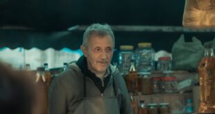 Senior man in Turkey's Bursa night market selling olives and oils.