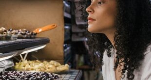 A young woman intently browsing a variety of pastries at an indoor market display.