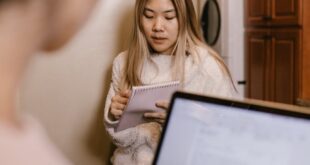 Young woman engaged in online learning at home with a laptop and notebook.