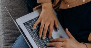 A person typing on a laptop while seated on a couch with casual attire, perfect for remote work imagery.