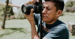 Photographer capturing images outdoors on a sunny day with camera.