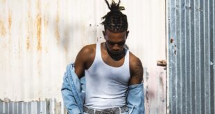 Stylish young man in trendy denim attire against a rustic metal background.