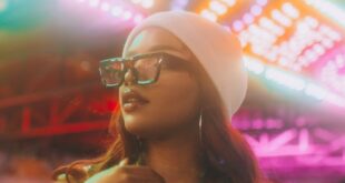 Fashionable woman in a vibrant night setting with colorful lights at a carnival in Atlanta.
