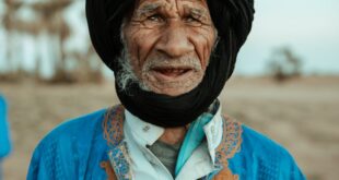 A striking portrait of an elderly nomadic man in traditional attire in the Mhamid desert, Morocco.