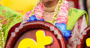 Woman in traditional attire holding decorative sign at a cultural festival in Dhaka.