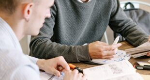 Two young men studying together at a table with books and notes.