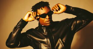 Confident man in a leather jacket and sunglasses posing in a modern fashion shoot.