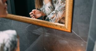 Female using skincare products in a relaxing bathroom with candlelight ambiance.