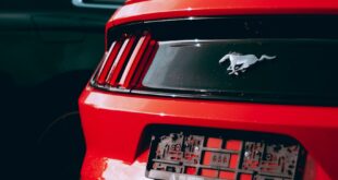 Vibrant red Ford Mustang with a distinctive emblem, captured in a parking lot.