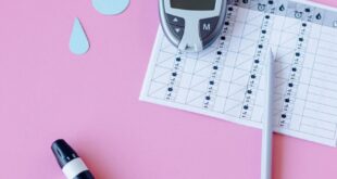 Flat lay of diabetes monitoring tools on a pink background.