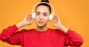 Trendy young woman in a red crop top enjoying music with headphones against a vibrant backdrop.