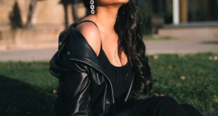 Fashionable woman sitting on grass in a black leather jacket and boots.