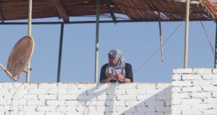 A woman stands on a rooftop, surrounded by rustic architecture in Louxor, Egypt.