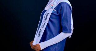 A young woman in a nursing uniform and headscarf posing confidently for graduation.