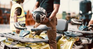 Man holding helmet beside quad bikes outdoors in Aburi, Ghana. Ready for adventure.