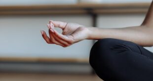 Close-up of a person's hand performing a yoga mudra next to a lit candle, evoking tranquility.
