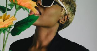 Fashionable woman in sunglasses posing with sunflowers on a white background in Accra.